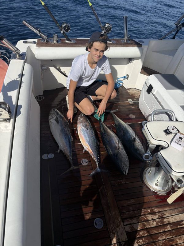 Young angler proudly holding a large Little Tunny catch while wearing a professional gimbal belt on a Blue Marlin fishing trip in Marbella.